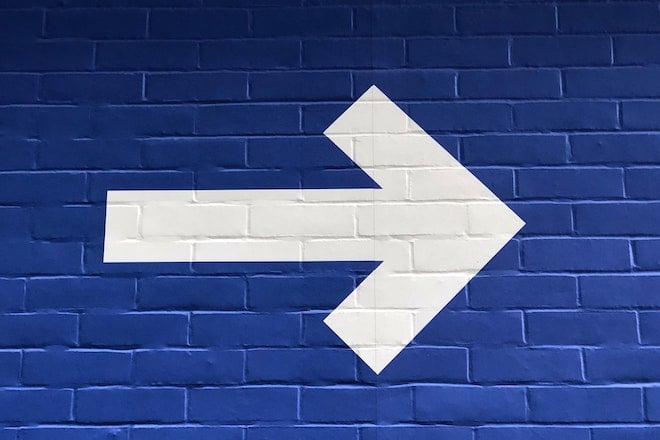 white arrow on blue brick background