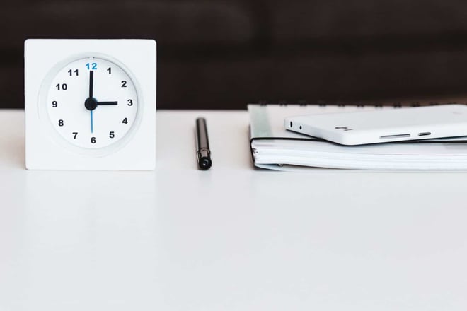 desk with clock, pen, notebook and phone