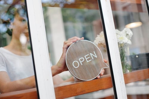 woman putting open sign in business window